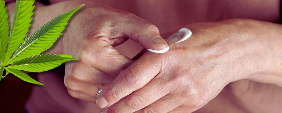 Right hand applying cannabis cream to sore wrist; open 1 : 1 topical jar on counter.
