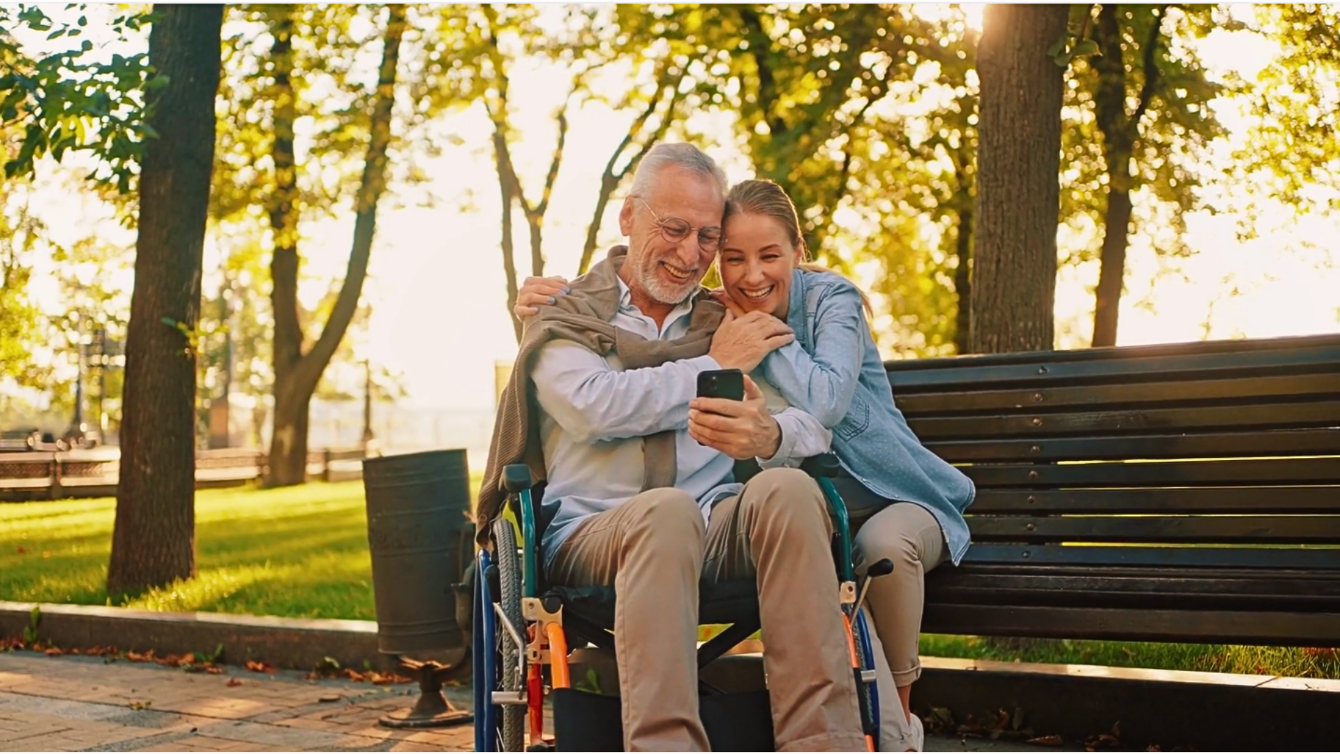 Elderly father in wheelchair with adult daughter at sunset